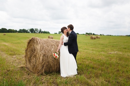 Bride and groom near hay on a rural fieldの写真素材