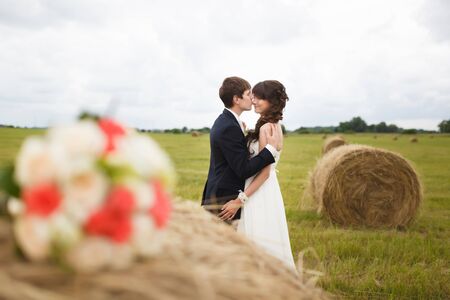 Bride and groom near hay on a rural fieldの写真素材