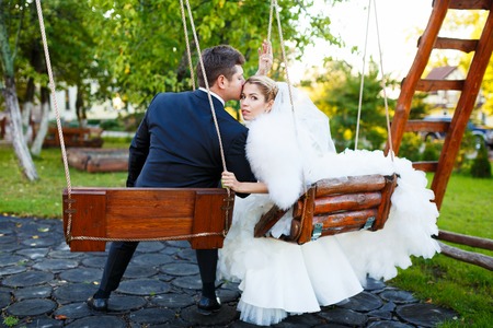 Happy young wedding couple riding on a swing in their wedding dayの写真素材