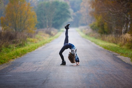 Young professional gymnast makes splits on the road at autumn timeの写真素材