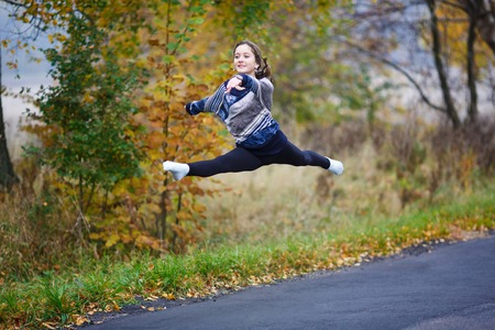 Young professional gymnast makes splits on the road at autumn timeの写真素材