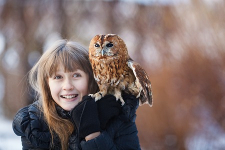 Cute girl standing with little owl in a parkの写真素材