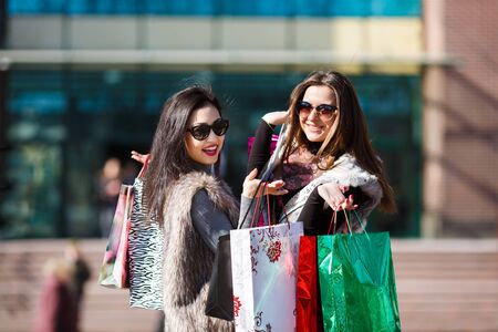 Young beautiful women holding shopping bags and smiling outdoorsの写真素材