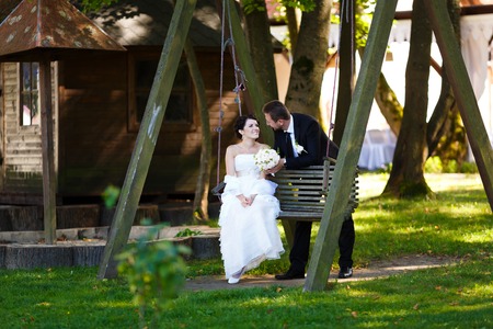 Bride and groom embracing on a swing on their wedding dayの写真素材
