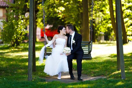 Bride and groom embracing on a swing on their wedding dayの写真素材