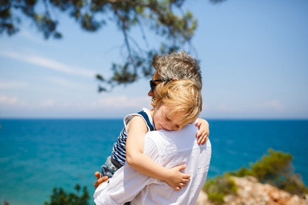 Father and son hugging on the blue sea backgroundの写真素材