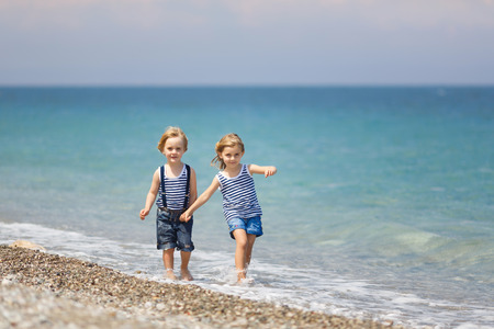 Little brother and sister walking on the beachの写真素材
