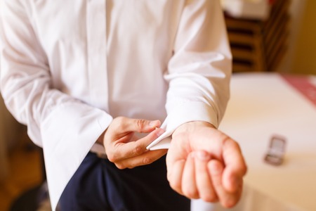 Man puts cufflinks on sleeve white shirtsの写真素材