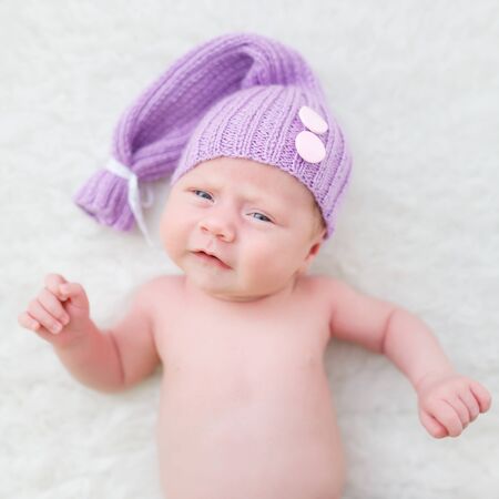 Portrait of an one month boy dressed in a violet hat on the white backgroundの写真素材