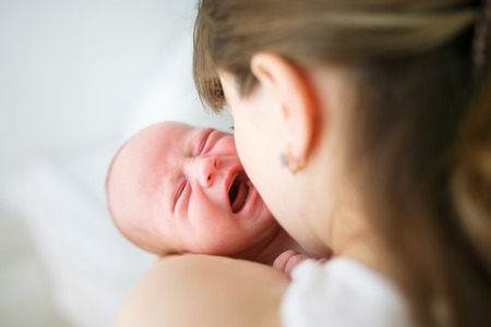 Mother holding her crying little son in studioの写真素材