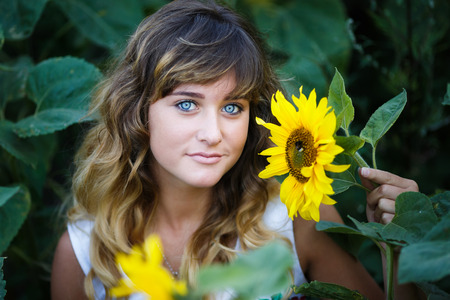 Attractive young girl in the field of sunflowers at summer timeの写真素材