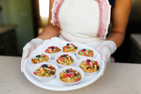 Young woman holding a tray with cupcakes at the kitchenの写真素材