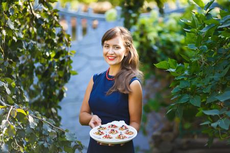 Young woman holding a tray with cupcakes in the gardenの写真素材
