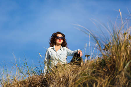 Young woman sitting in a dune at autumn timeの写真素材