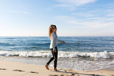 Young smiling woman walking on the seacoast at autumn timeの写真素材
