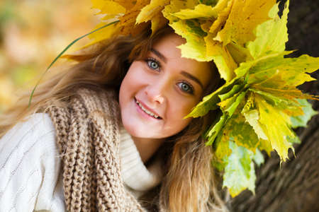 Portrait of the young smiling girl dressed in a wreath at autumn timeの写真素材