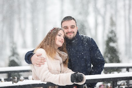 Happy young couple kissing on a bridge in snowfallの写真素材