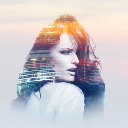 Double exposure of young woman with buildings of metropolisの写真素材