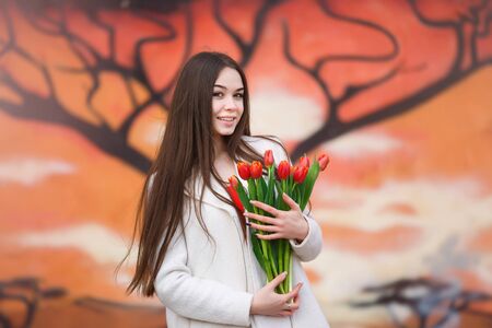 Young happy woman with bouquet of tulips outdoorの写真素材