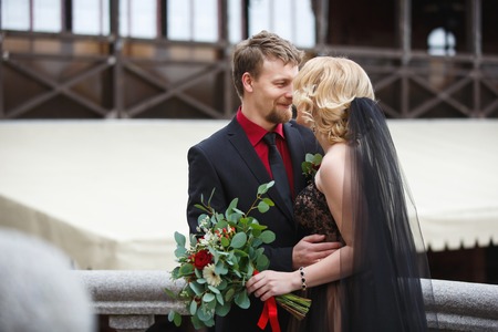 Embracing and smiling bridal couple with bouquet outdoorの写真素材