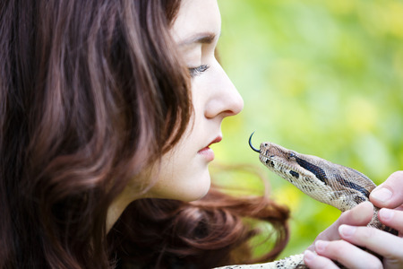 Attractive teenage girl holding the python close near the face