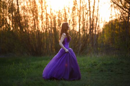 Running attractive girl dressed evening gown at sunsetの写真素材