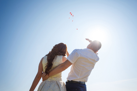 Romantic wedding couple looks at the sky and watchs go the flying air-balloonsの写真素材