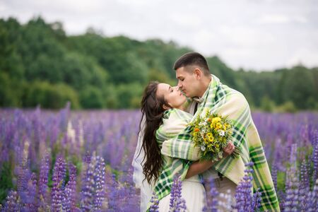 Happy wedding couple hugging in the lupine fieldの写真素材