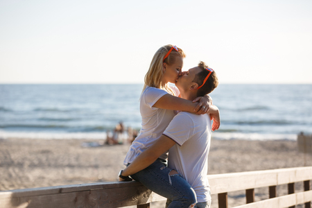 Young couple are kissing by the wooden fence on the beach, summer timeの写真素材