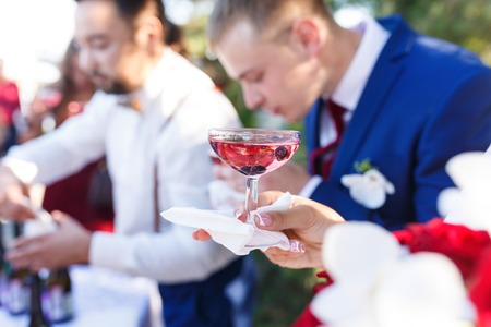 Hands with glasses of vine at the open air wedding banquetの写真素材