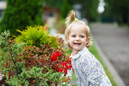 Portrait of the happy little girl near the flower bedsの写真素材