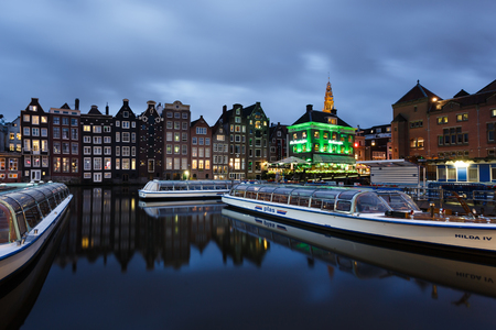 Amsterdam, Netherlands - July 01 2016: Tourist boats in the marina on the background of traditional Dutch houses, evening timeのeditorial素材