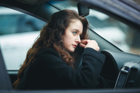 Sad young woman driving car in rainの写真素材