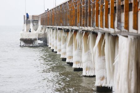 Some people are walking on the ice-covered pierの写真素材