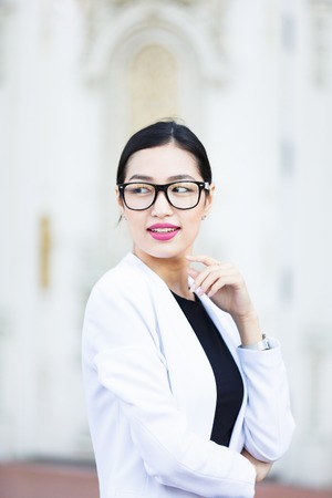 Asian young woman against the white door backgroundの写真素材