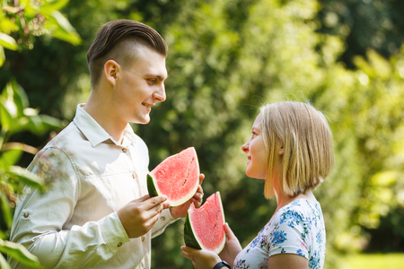 Couple is eating watermelon in a summer parkの写真素材