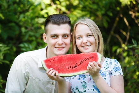 Couple is eating watermelon in a summer parkの写真素材