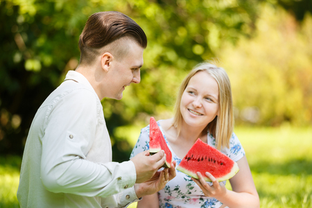 Couple is eating watermelon in a summer parkの写真素材