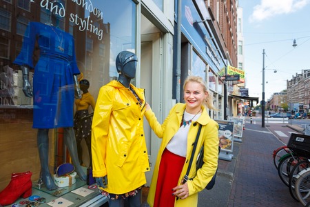 Amsterdam, Netherlands - September 23 2017: Young cheerful woman is looking at clothes dressed in a dummy near a clothing storeのeditorial素材