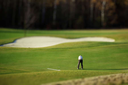 Golf player putting ball to the holeの写真素材