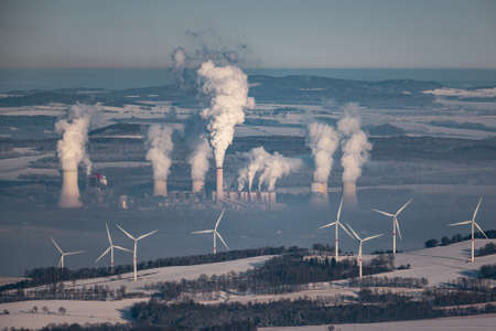 A giant smoking coal-fired power plant near the Czech-Polish border. In the foreground wind turbines...