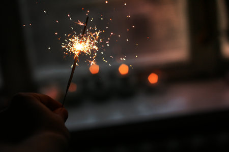 A person holding a sparkler near a window.の写真素材