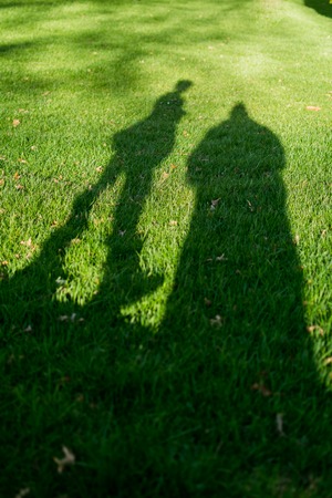 Shadows of two people in the grass on a very sunny dayの写真素材