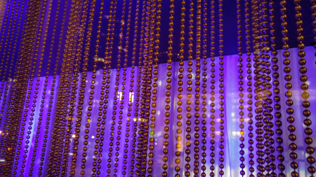 A curtain of small metal beads, hanging in front of a reflective purple and blue backgroundの写真素材