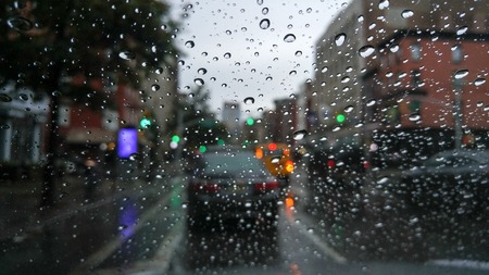 Looking at traffic through a windshield covered with raindrops on a dreary and gloomy dayの写真素材