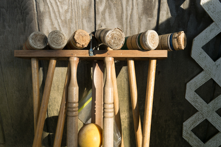 Old well-used Croquet Mallets in a rack, leaning against a wooden wall, medium shot