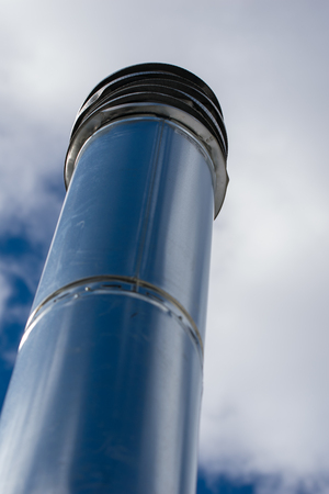Long chimney pipe reaching into a cloudy blue sky, close-up, Bronx, NYの写真素材