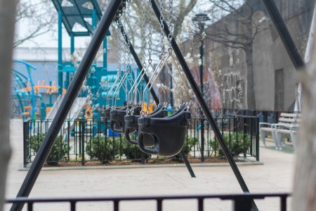 Empty swings on a New York City playground on a rainy day