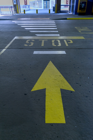 Big yellow arrow street markings pointing toward a stop sign