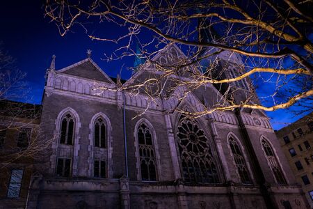 Creepy nighttime shot of an old church, with tree branches in the foregroundの写真素材